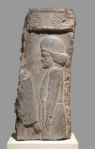 A carved limestone relief showing a figure in procession at Persepolis.